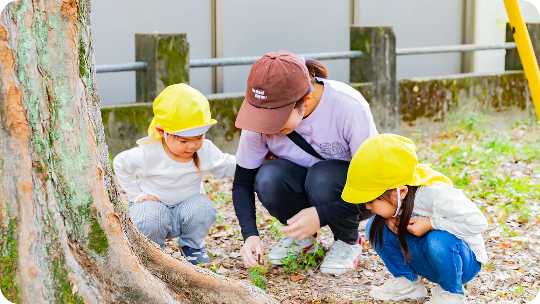 園児が自分の頬に指を当て、面白い顔を向けている様子