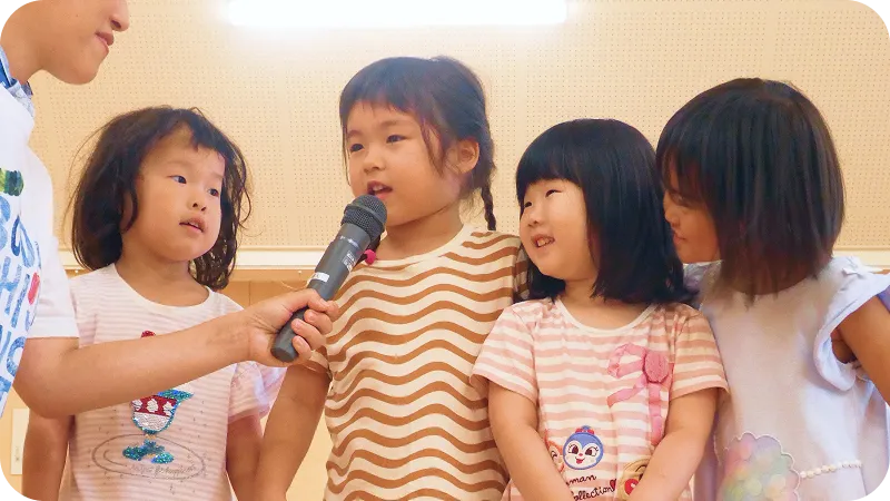 保育室でマイクを持って誕生日の発表をする園児たちの様子