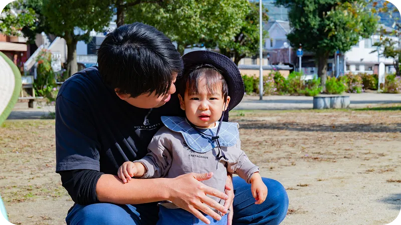 公園で保育士と乳児が触れ合っている様子