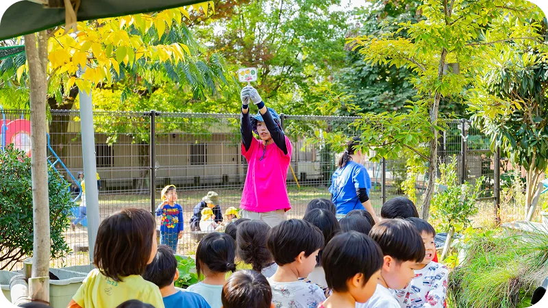 園庭で幼児たちが先生の話を聞いている様子