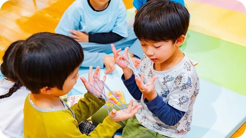 幼児があやとりで遊んでいる様子
