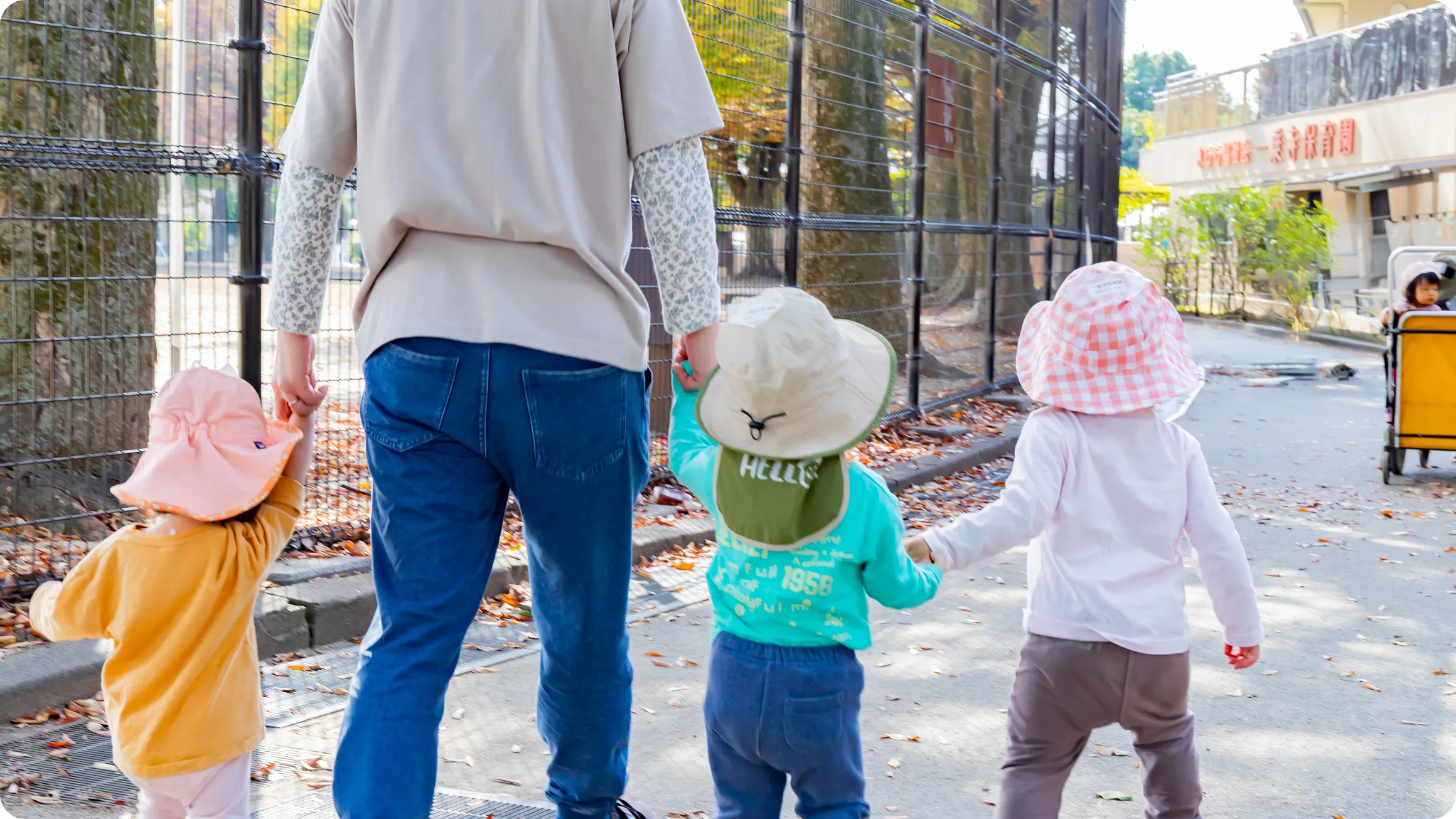 保育士と子どもたちが手をつなぎながら散歩している和やかな様子