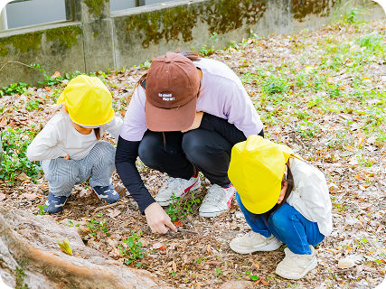 園児と保育士が地面に座り込む様子