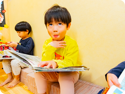 園児が本を読みながら何かを考えている様子